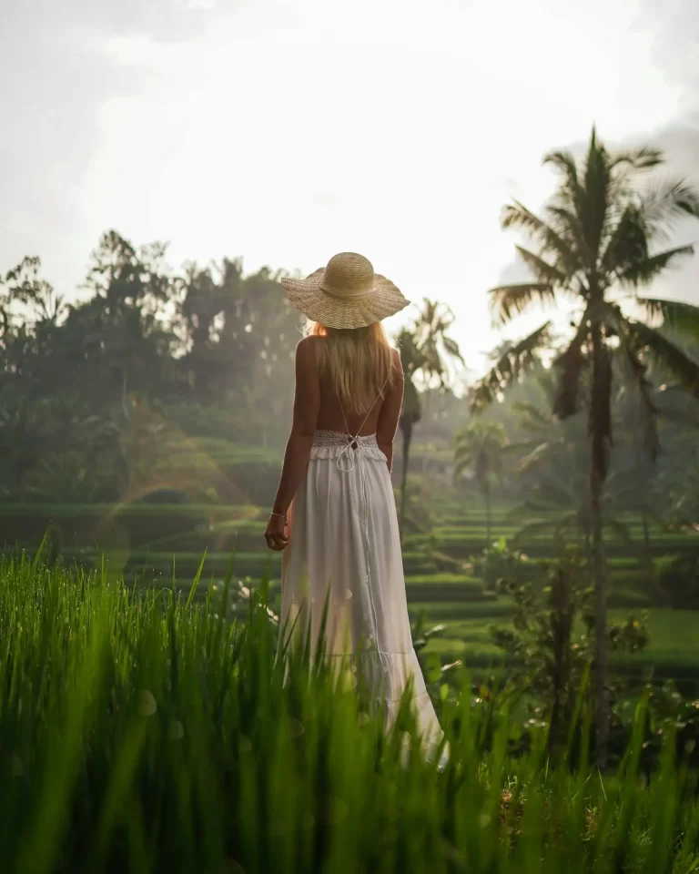 Woman in a white dress overlooking Bali rice terraces at sunrise