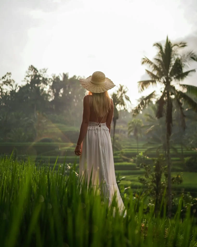 Woman in a white dress overlooking Bali rice terraces at sunrise